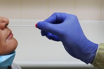 A nurse inserts a swab into a person's nose to test them for a virus.