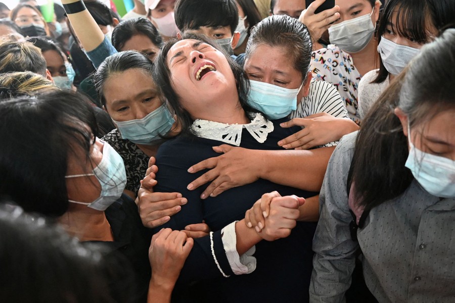 A woman leans back and cries, surrounded and held by several other mourners.