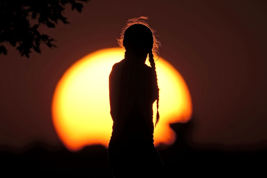 A girl in silhouette in front of the setting sun