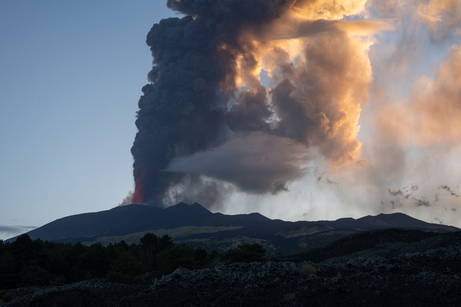 Lava, steam, and ash spew from the top of a volcano.
