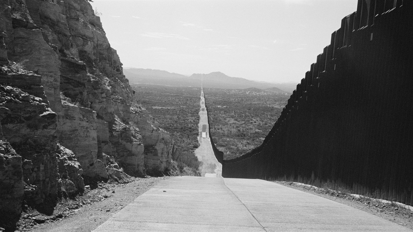 In a black-and-white photo, the long road between the United States and the Mexico border