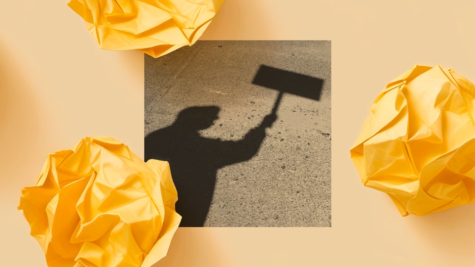 A shadow of a person holding a protest sign appears on a sidewalk