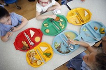 An overhead shot of students sitting with colorful lunch trays at a cafeteria table