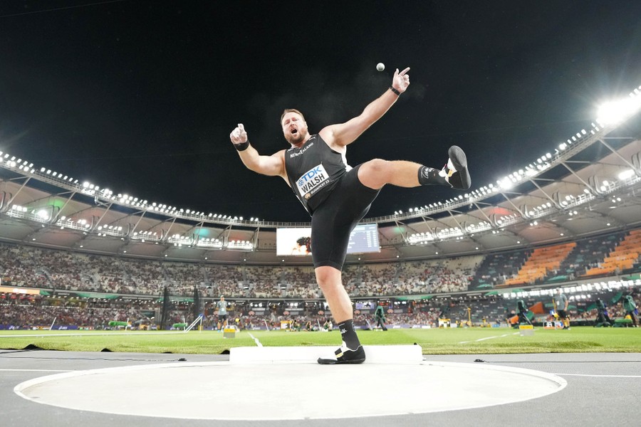 A competitor balances on one foot, still spinning after throwing a shot put.