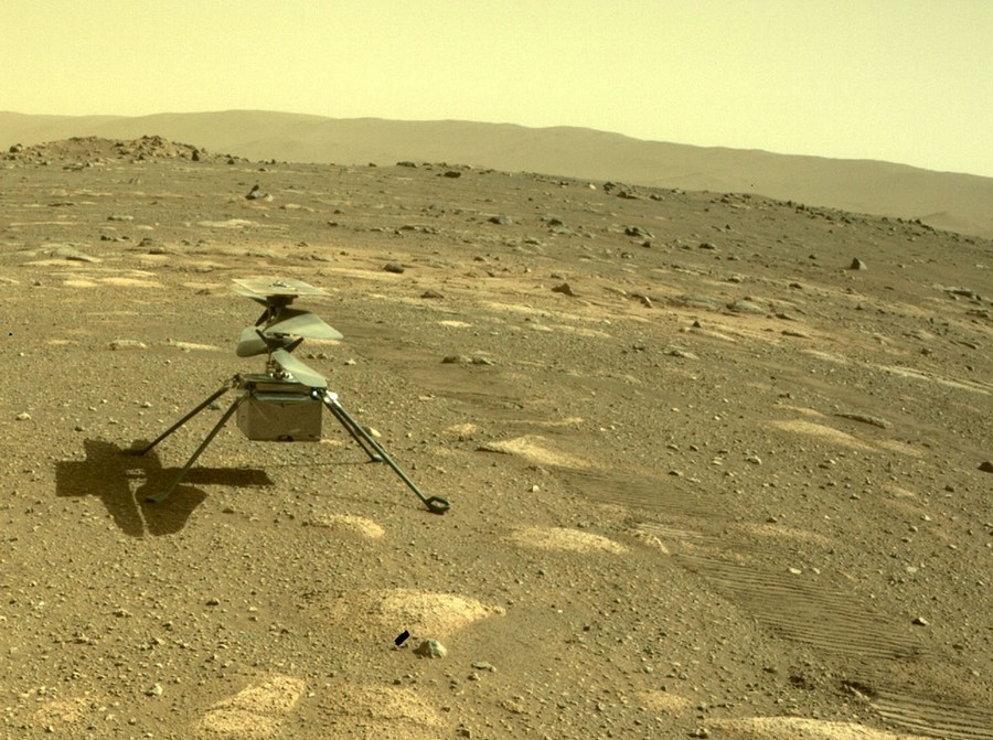 A tiny twin-rotor helicopter sits on the Martian surface.