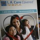 Two women converse behind a sign for the L.A. Care Health Plan.