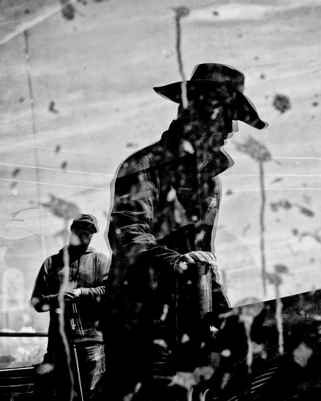 A black-and-white photo of the silhouette of a man with a cowboy hat on