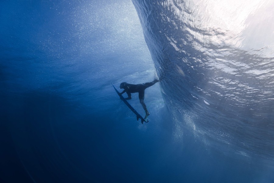An underwater view of a surfer diving beneath a large wave