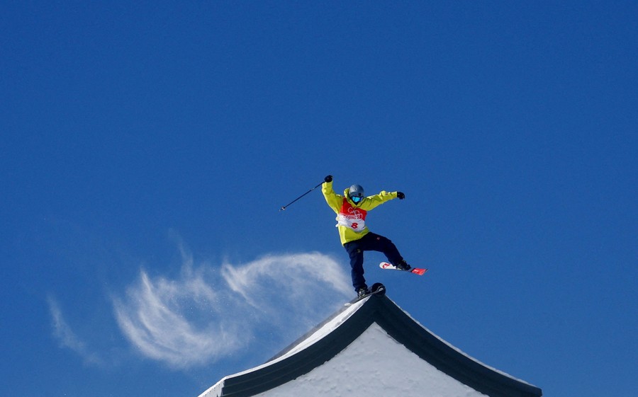 A skier crosses the roof of an obstacle on a course.