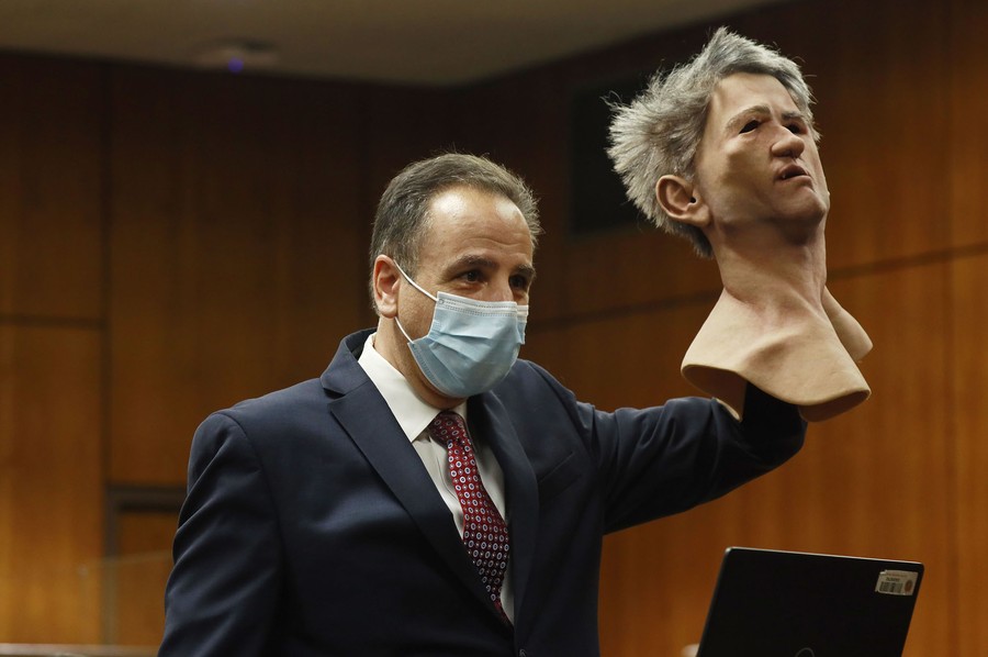 An attorney holds up a full-head latex mask inside a courtroom.