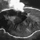 A black and white photo of Kasatochi Island with smoke rising from its caldera.