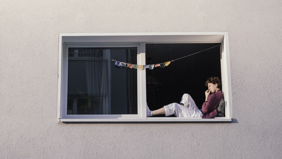 A woman lounges in the window of an apartment building