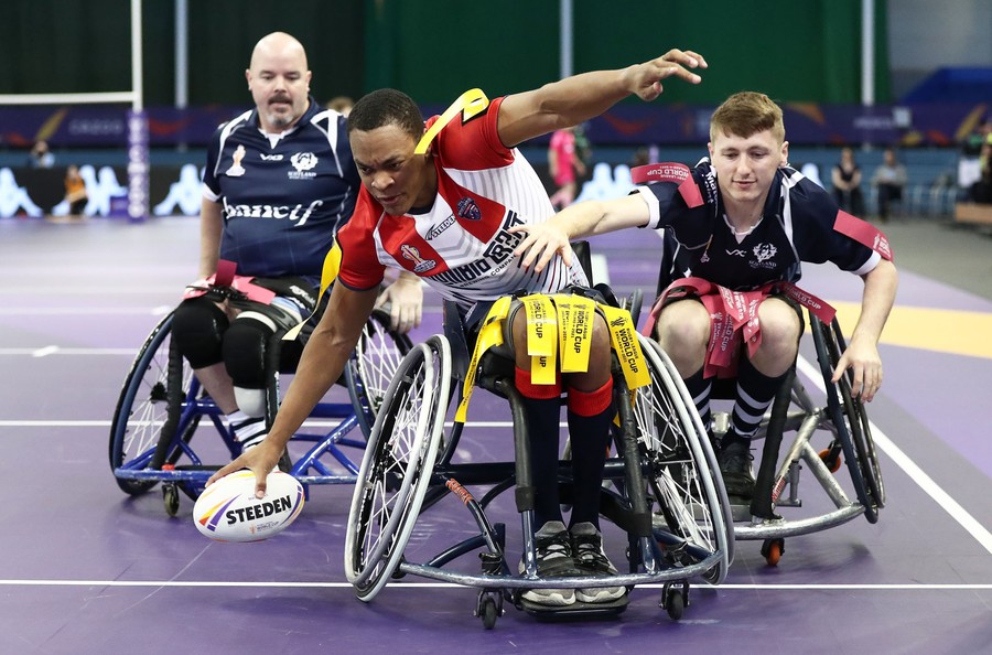 Three competitors in wheelchairs play a game of rugby.