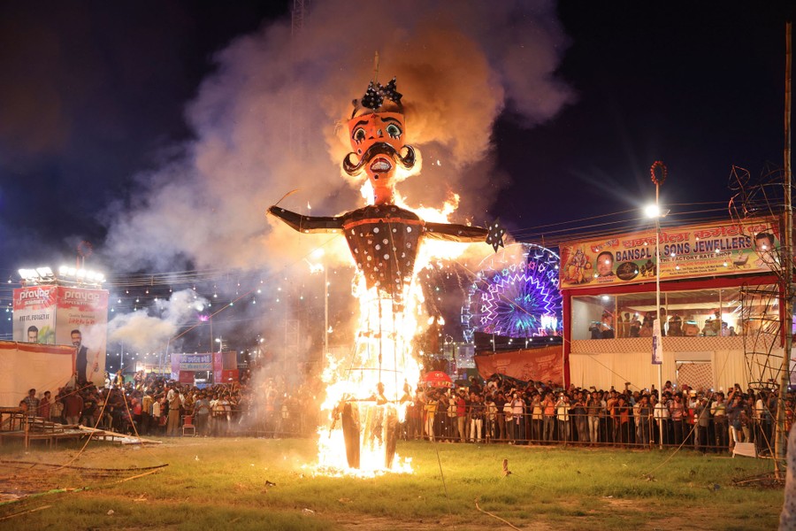 An effigy of a mythological figure burns as a crowd watches.