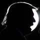 Donald Trump's head silhouetted against a spotlight as he speaks into a microphone