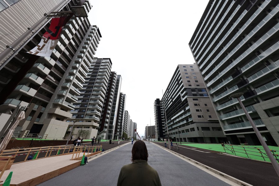 A person stands in a road among many multi-story residential buildings.