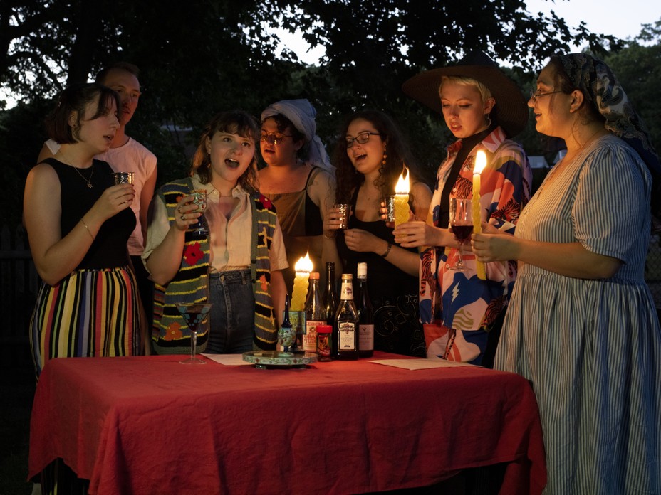 a group of young adults signing with candles around a table