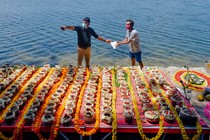 Two men stand in front of 560 urns containing the ashes of Indians who died of COVID-19