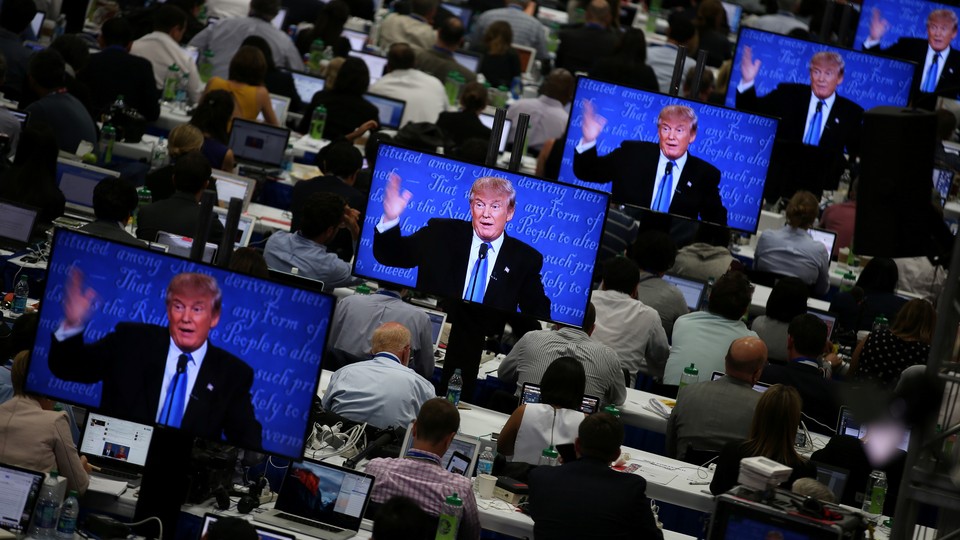 Reporters watch Donald J. Trump on television screens during the first presidential debate.