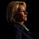 Betsy DeVos speaking at podium against a black background
