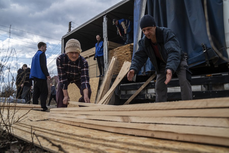 People work together to offload lumber from a delivery truck.