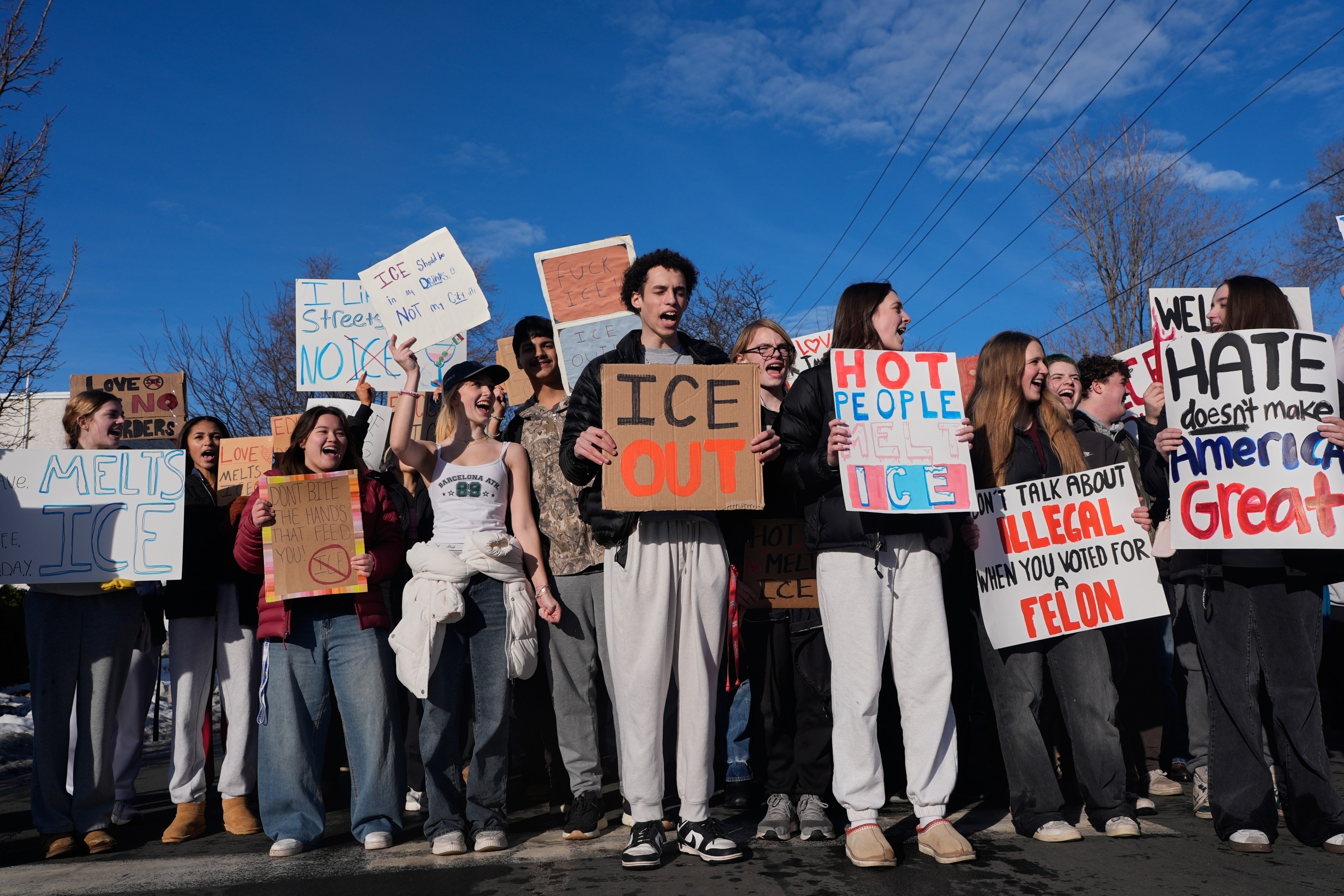 A group of students stand together during a protest, holding signs.