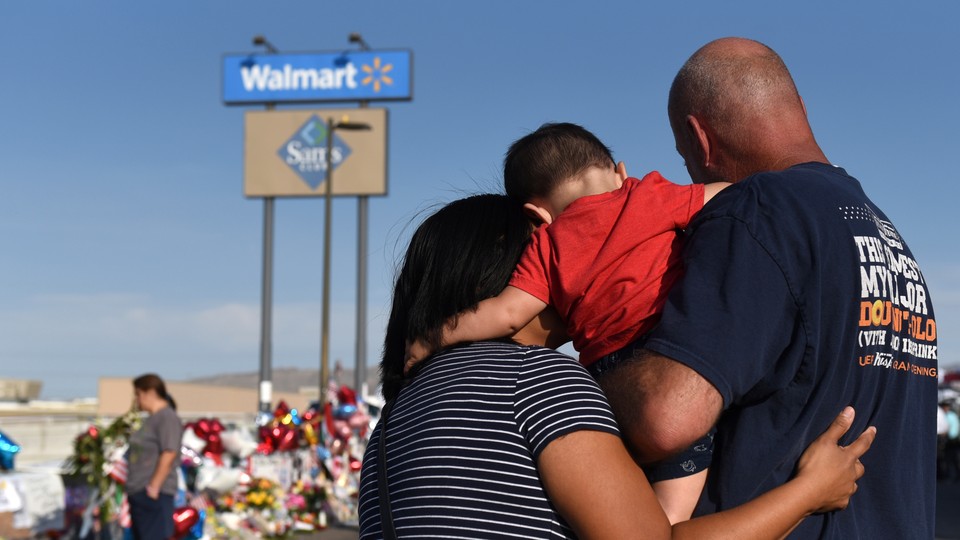 A man, woman, and child visit an impromptu memorial in El Paso.
