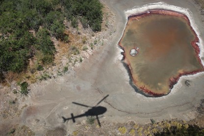An air interdiction helicopter from U.S. Customs and Border Protection flies past a drought-stricken pond by the U.S.-Mexico border