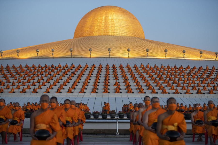 Hundreds of Buddhist monks gather in rows beneath a golden dome.