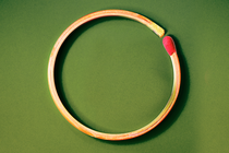 a match bent into a circle, on a green background