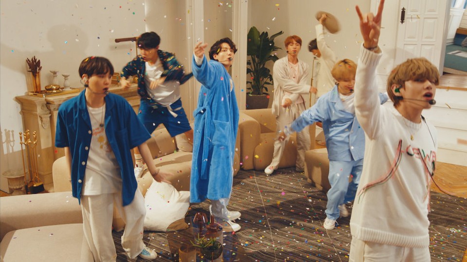 The seven members of BTS performing in pajamas as confetti rains down