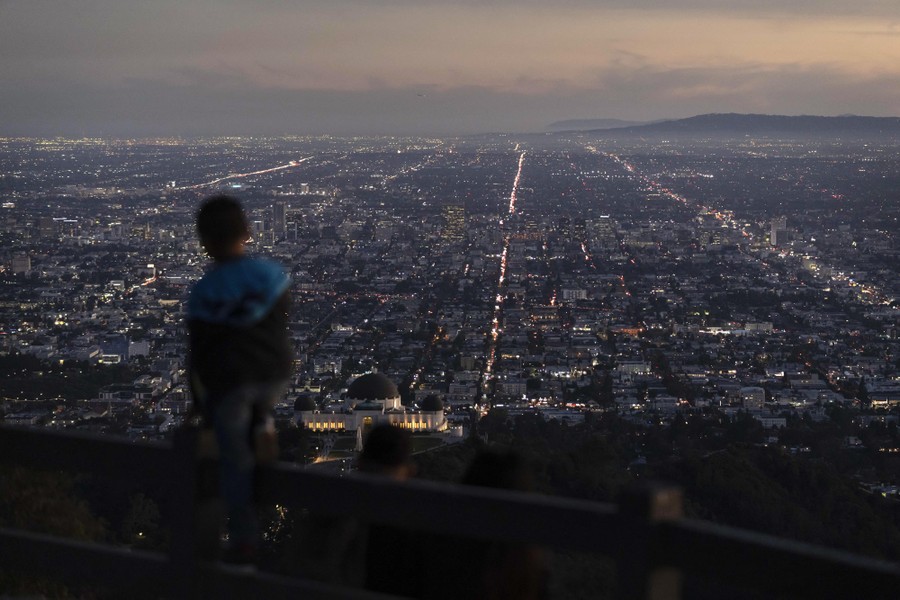 A boy takes in the view of the Los Angeles skyline from a hilltop.
