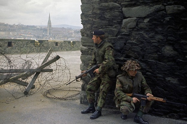 Two soldiers by a wall and barbed wire
