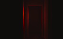 Front view of a door illuminated with red lighting in dark corridor.