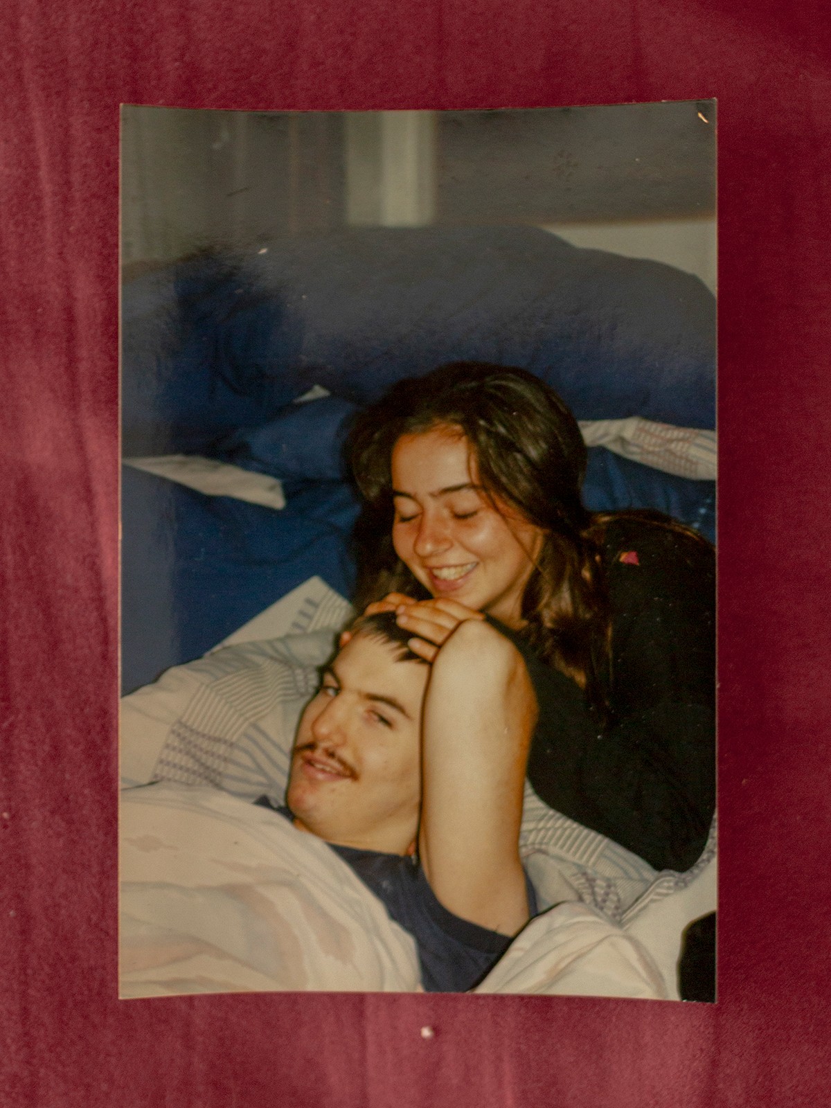 photo of young woman smiling with hands on top of young man's head, his eyes open