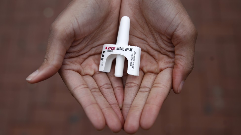 Hands holding a dose of Narcan nasal spray