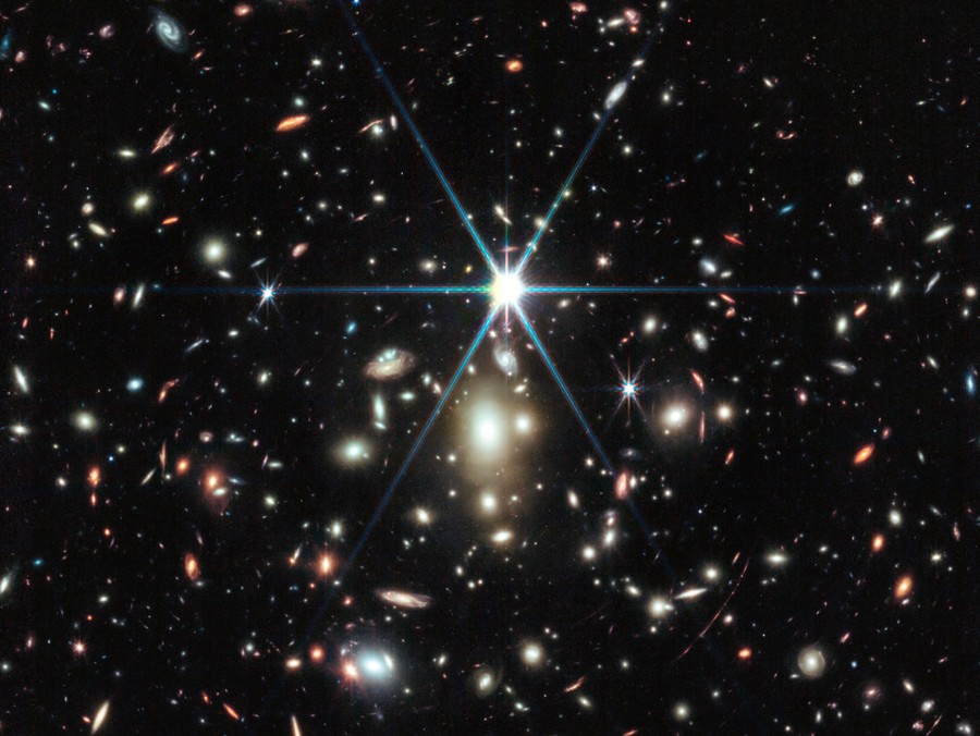 Many galaxies clustered together, and several stars, closer by