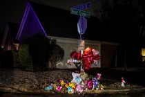 Balloons, flowers, and stuffed animals adorn a stop sign at the corner of Castlegate Lane and Bear Creek Cove.