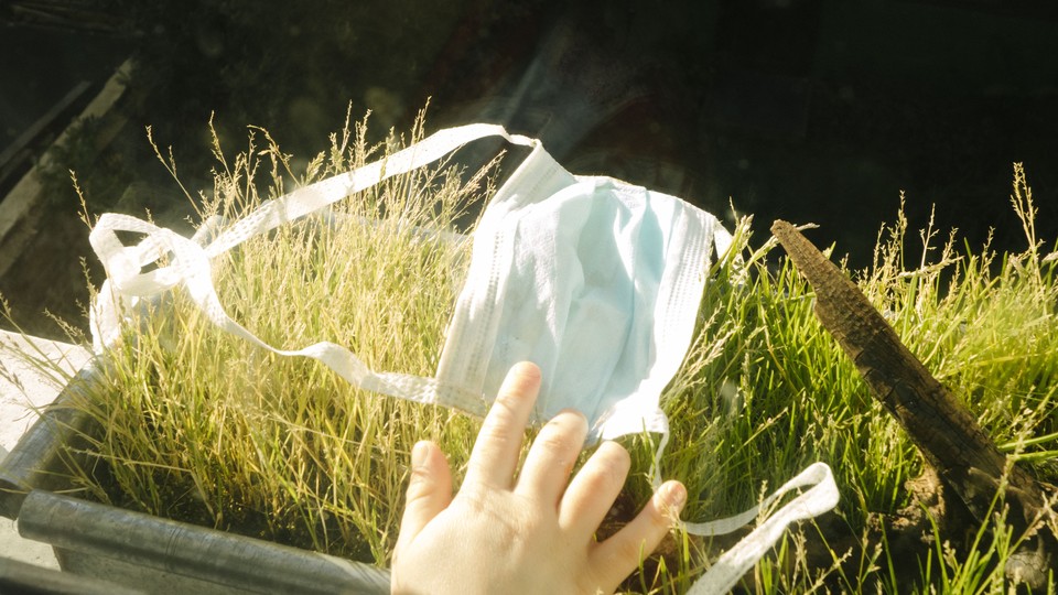 A hand, a face mask, and grass.