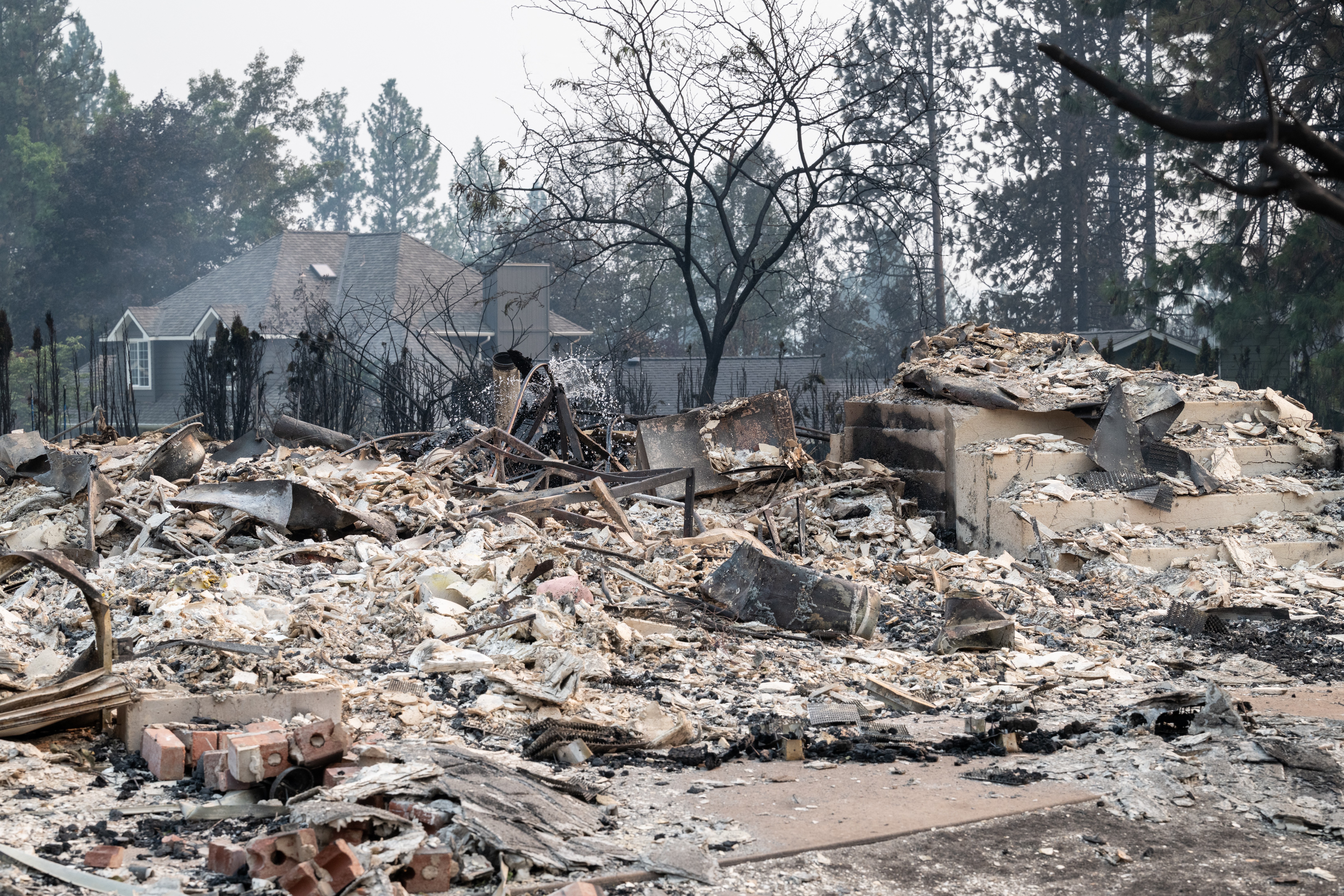 The rubble of a burned house smolders.