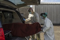 Medical staff push a stretcher with a deceased patient into a car outside of a COVID-19 intensive-care unit in Houston, Texas.