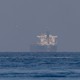 Color photograph of a big ship appearing to materialize through a fog in the Strait of Hormuz.