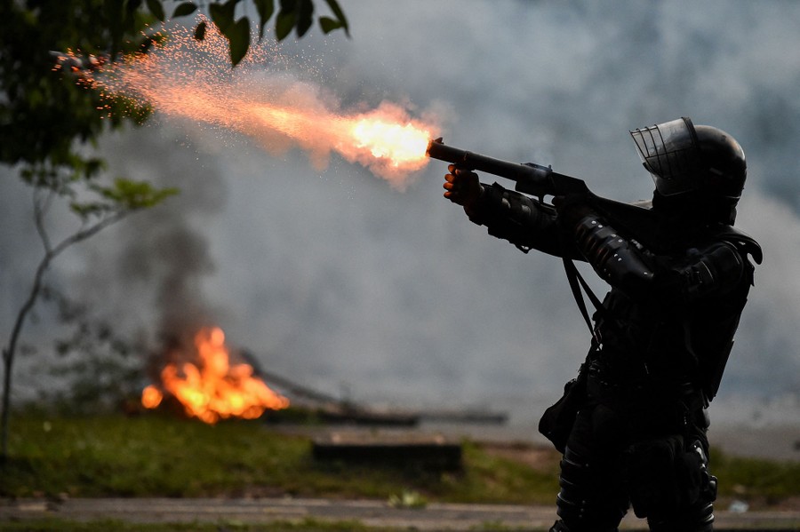 A riot police officer fires tear gas.