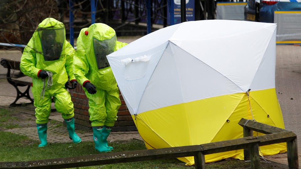 Two people in fluorescent suits approach a police tent