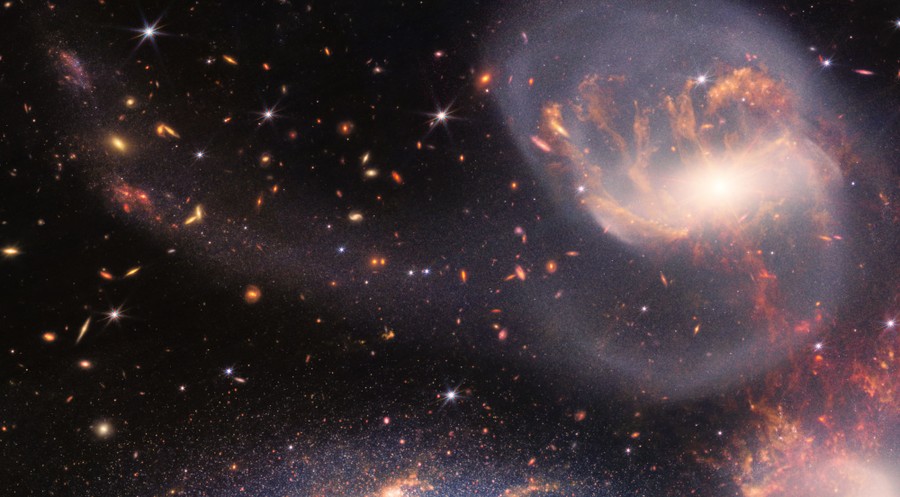 A close view of a distorted galaxy and hundreds of distant galaxies.