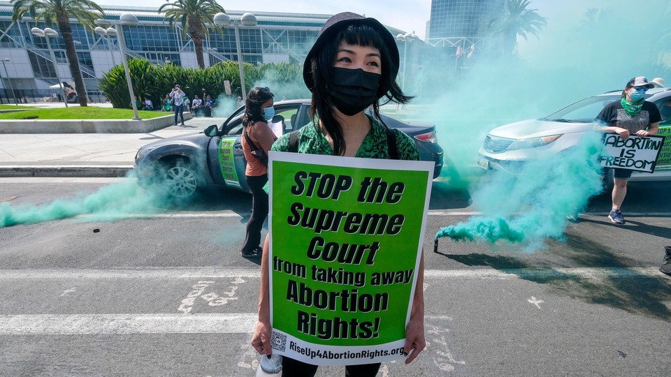 Picture of a masked girl with a sign that reads "STOP the Supreme Court from taking away Abortion Rights!"