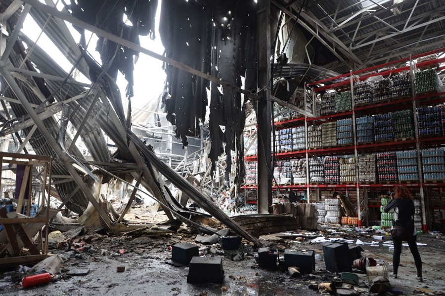 A person takes a picture inside a damaged warehouse after a missile strike.