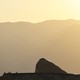 A Death Valley outcropping in front of a mountain, in hazy yellow heat