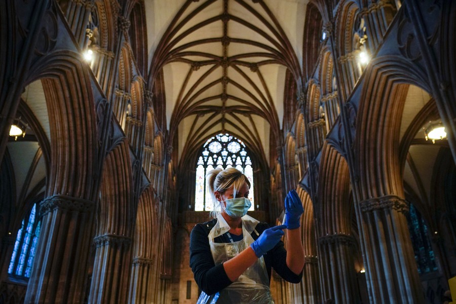 A nurse draws vaccine into a syringe inside a cathedral.