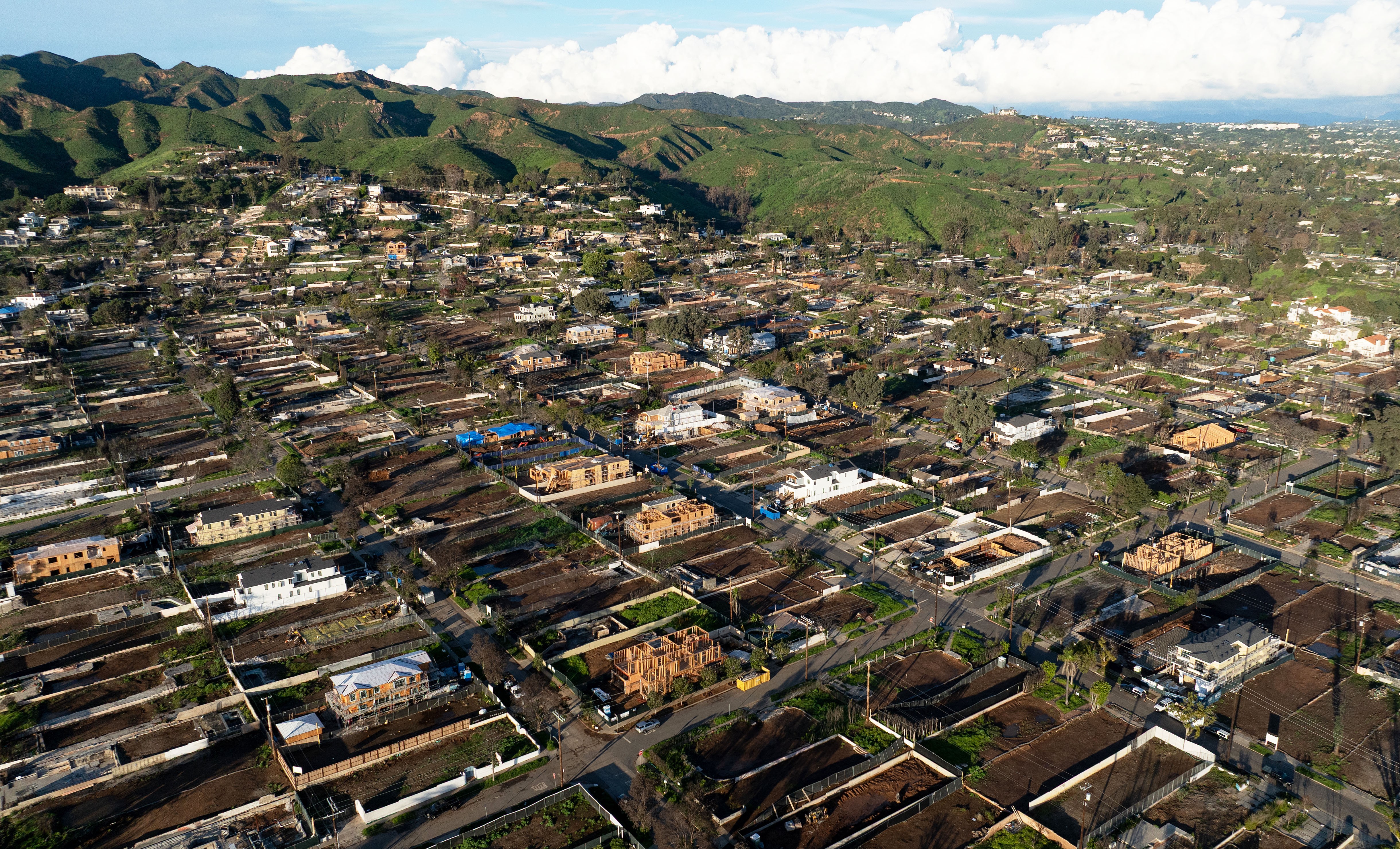 An aerial view shows empty lots and new homes under construction on a California hillside.